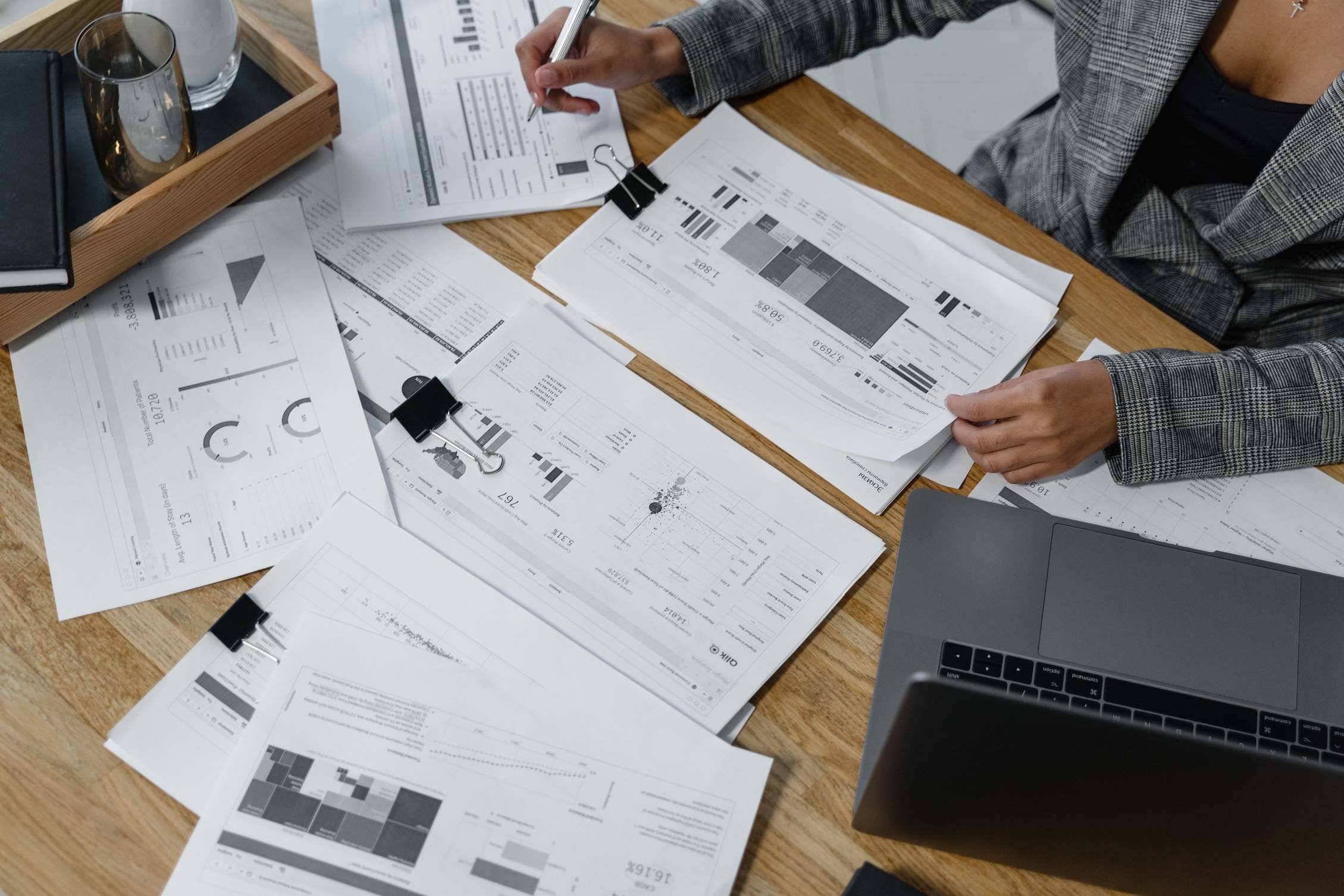Schreibtisch mit Laptop, Finanzberichten und Dokumenten auf einer Holzoberfläche